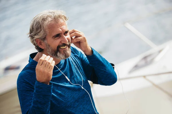 Gelukkige Senior atleet luisteren muziek over oortelefoons. — Stockfoto