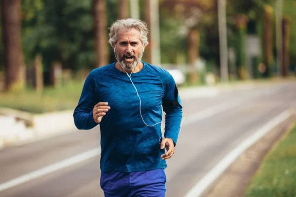 Aktywny starszy mężczyzna jogging w słoneczny dzień — Zdjęcie stockowe