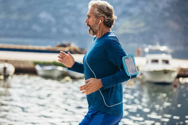 Actieve senior man joggen op de pier op een zonnige dag — Stockfoto