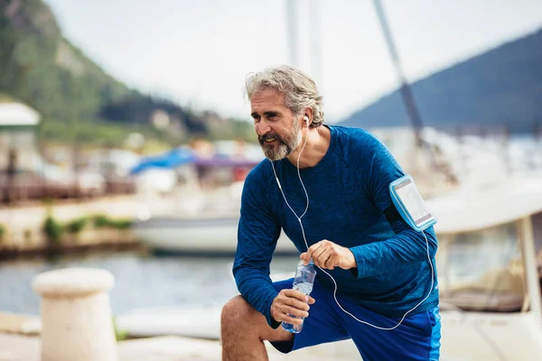 Fit dorstige Senior man drinkwater voor het hardlopen. Actieve oude — Stockfoto