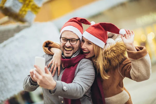 Jonge mooie paar met Santa hoeden maken selfie foto in de — Stockfoto