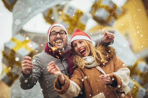 Jonge mooie paar met Santa hoeden het houden van sprinklers in de — Stockfoto