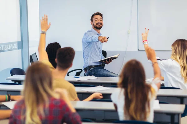 Grupo de estudantes levantando as mãos em sala de aula sobre palestra — Fotografia de Stock