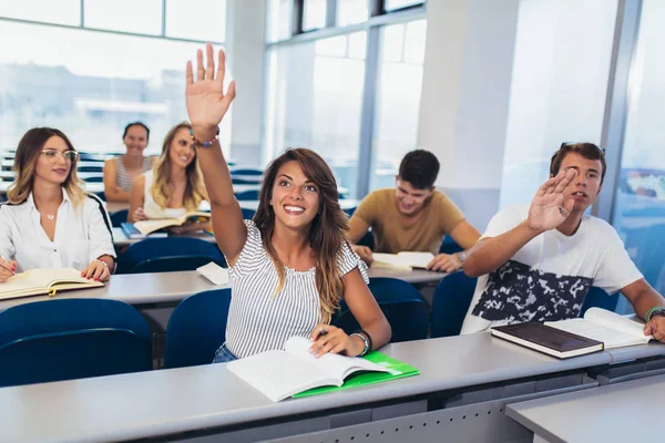 Skupina studentů zvyšování rukou ve třídě na přednášku — Stock fotografie