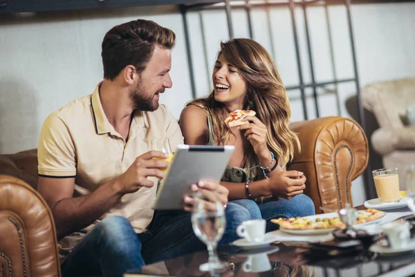 Tiro de una joven pareja feliz usando tableta digital y comiendo piz — Foto de Stock