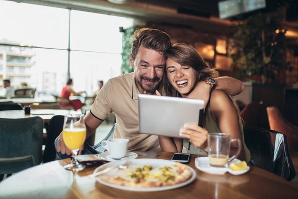 Aufnahme eines jungen glücklichen Paares, das ein digitales Tablet benutzt und Piz isst — Stockfoto