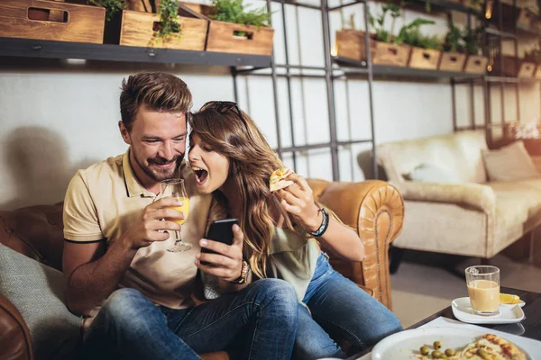 Shot of a young happy couple using digital tablet and eating piz — Stock Photo, Image