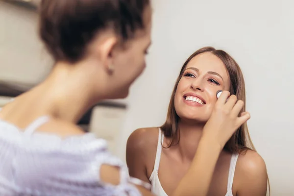 Twee lachende meisjes die make-up thuis toepassen — Stockfoto