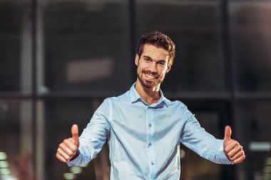 Genç yakışıklı iş adamı dışarıda baş parmağını kaldırıyor..