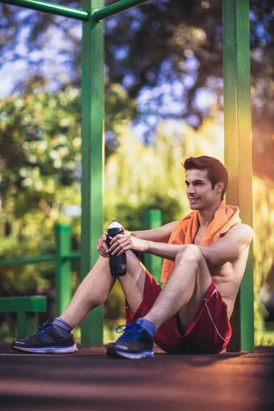 Уставший спортсмен в спортивной одежде отдыхает после тренировки на открытом воздухе . — стоковое фото