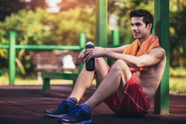 Moe atletische man in sportkleding rusten na training buiten. — Stockfoto