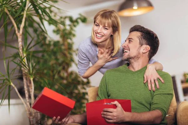 Feliz hombre recibiendo un regalo de su novia mientras está sentado — Foto de Stock