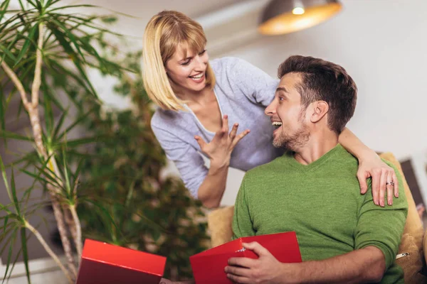 Gelukkige man ontvangen van een geschenk van zijn vriendin terwijl zittend — Stockfoto