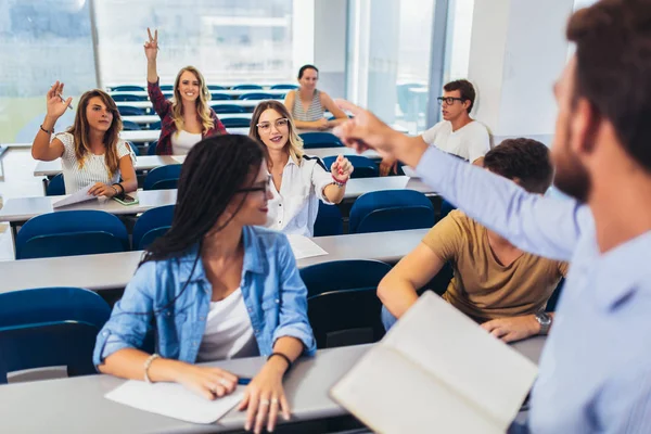 Groep studenten verhogen handen in de klas op Hoorcollege — Stockfoto