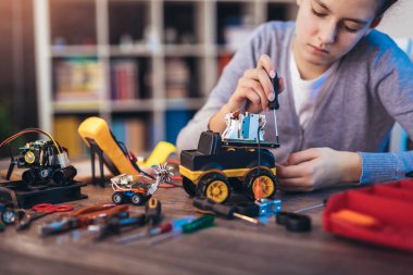 Kız teknik oyuncaklar yapıyor. Masa dolusu teknik oyuncak.