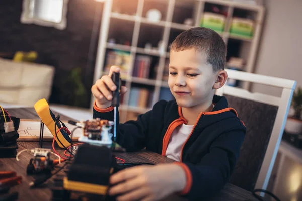 Glücklich lächelnder Junge konstruiert technisches Spielzeug. Technisches Spielzeug auf der Lasche — Stockfoto