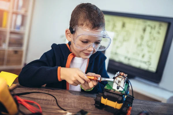 Happy smiling boy constructs technical toy. Technical toy on tab — Stock Photo, Image