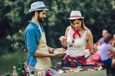 Mutlu arkadaşlar et pişiriyor barbekü partisinin tadını çıkarıyor.
