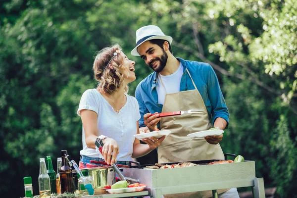 Amigos felizes se divertindo grelhando carne desfrutando de churrasqueira — Fotografia de Stock