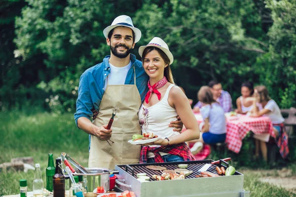 Mutlu arkadaşlar et pişiriyor barbekü partisinin tadını çıkarıyor.