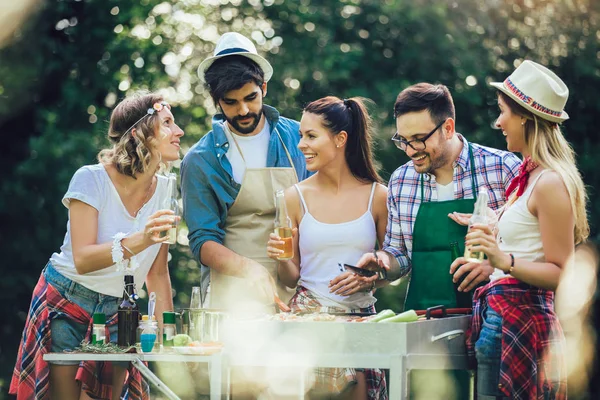 Щасливі друзі весело смажать м'ясо, насолоджуючись вечіркою барбекю — стокове фото