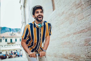 Scooter süren neşeli yakışıklı bir adam, eğleniyor. Seçici odak