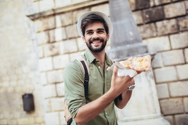 Jonge knappe casual man eten pizza outdoor — Stockfoto