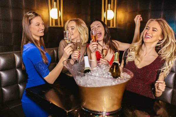 Mujeres felices tintineando copas de champán y celebrando por la noche — Foto de Stock