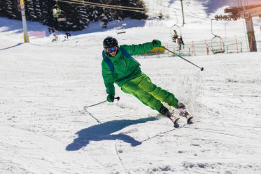 Yüksek dağlarda güneşli bir günde kayak yapan kayakçı. 