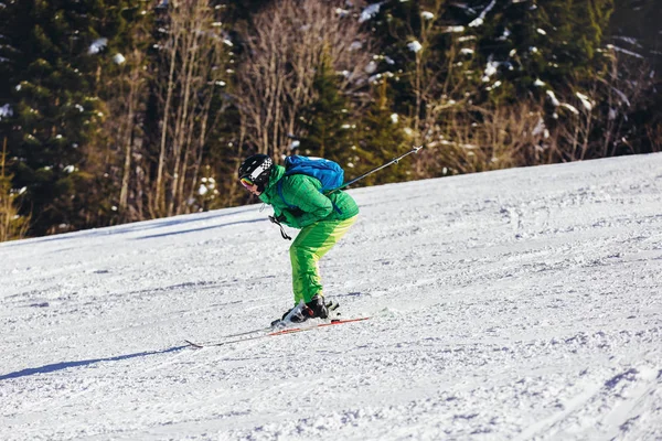 Esquiador esquiando cuesta abajo durante el día soleado en las altas montañas — Foto de Stock