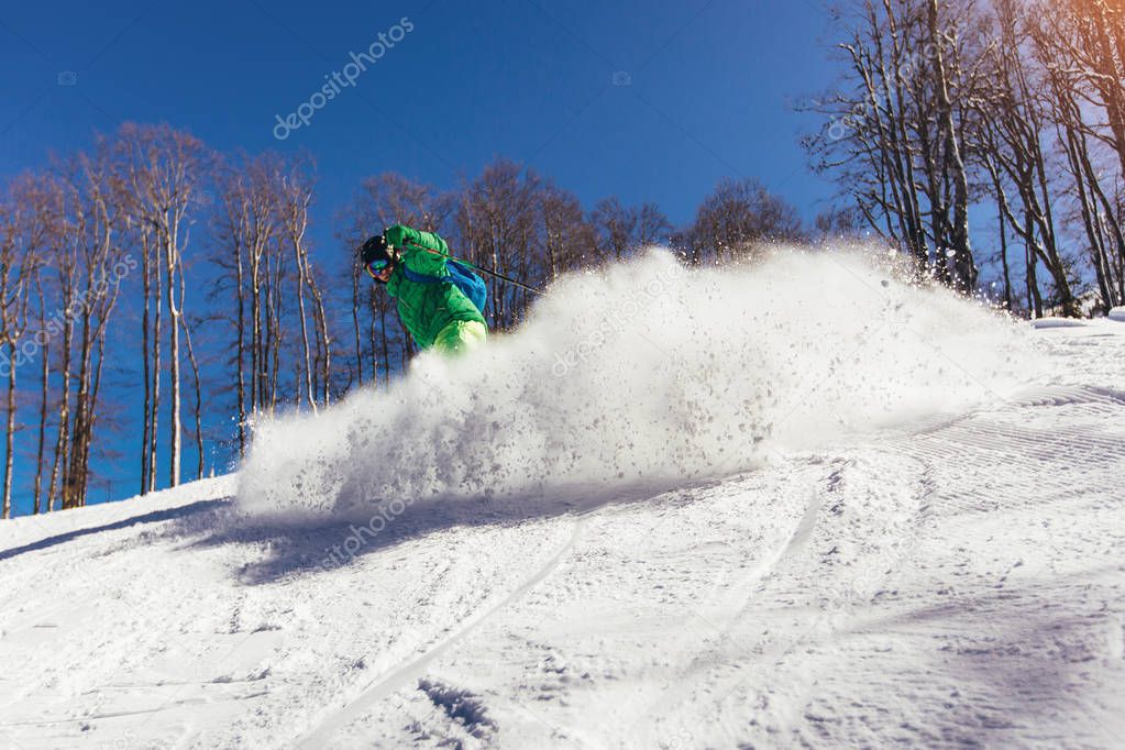 Skier skiing downhill during sunny day in high mountains 