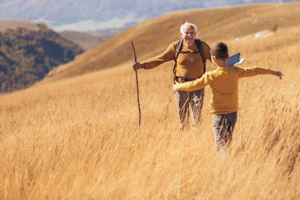 Hombre mayor con nieto en caminata por el campo en otoño. —  Fotos de Stock