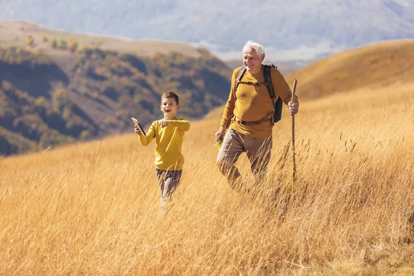 Hombre mayor con nieto en caminata por el campo en otoño. —  Fotos de Stock