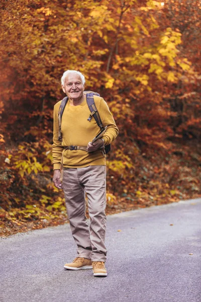 Homem sênior caminhadas na floresta de outono . — Fotografia de Stock