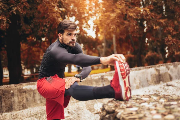 Sporcu adam sonbaharda parkta esniyor, egzersiz yapıyor.. — Stok fotoğraf