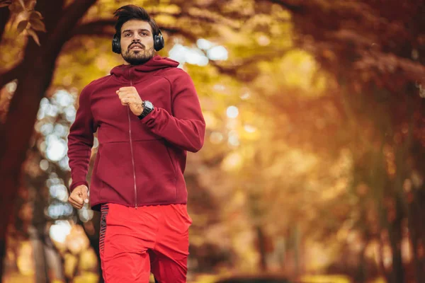 Jonge man loopt in het park tijdens herfst ochtend — Stockfoto