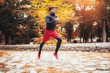 Sporcu adam sonbaharda parkta esniyor, egzersiz yapıyor.. 