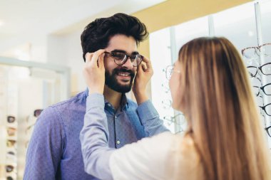 Kadın göz doktoru insana optik gözlük seçmesinde yardım ediyor.
