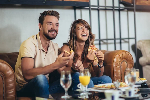 Casal comendo pizza no café moderno. Eles estão rindo e comendo — Fotografia de Stock