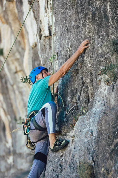 Homem sênior com uma corda subindo na rocha . — Fotografia de Stock