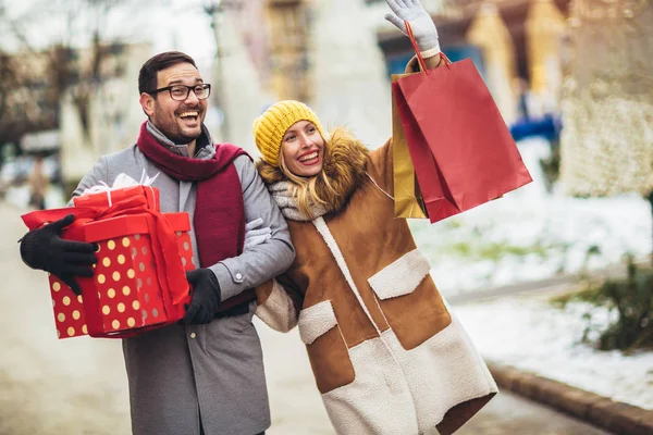 Νεαρό ζευγάρι ντυμένος σε χειμωνιάτικα ρούχα κρατώντας κουτιά δώρων — Φωτογραφία Αρχείου