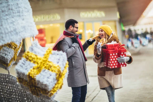 Jovem casal vestido com roupas de inverno segurando caixas de presente outdo — Fotografia de Stock