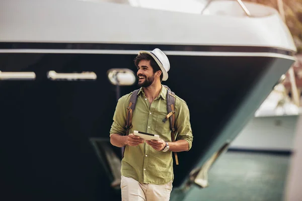 Jeune homme marchant près du port d'une station balnéaire touristique avec — Photo