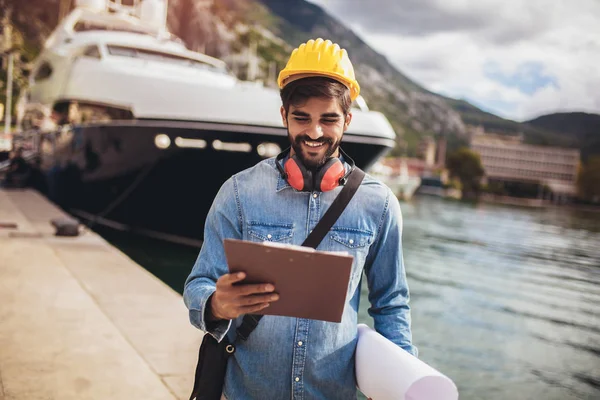 Přístavní inženýr drží papír, stavební práce, usmívá se. — Stock fotografie