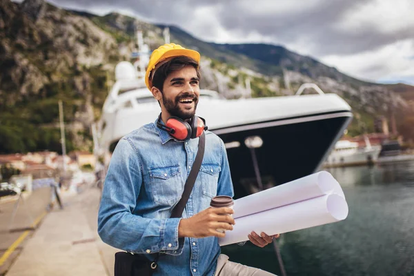 Haveningenieur die het papier vasthoudt, bouwwerkzaamheden, glimlachen. — Stockfoto