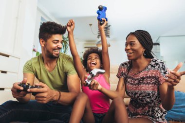 Aile birlikte video oyunları oynarken kanepede oturan gülümseyen