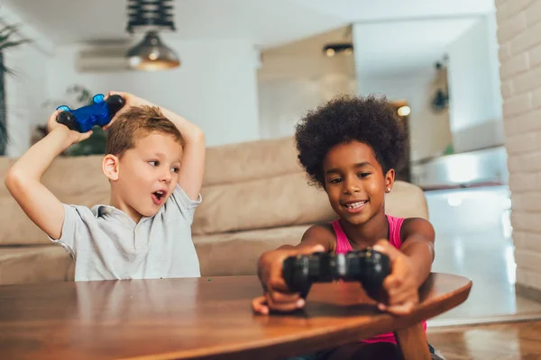 Niño y niña sentados en la sala de estar jugando videojuegos juntos — Foto de Stock