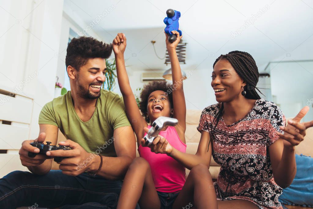 Smiling family sitting on the couch together playing video games