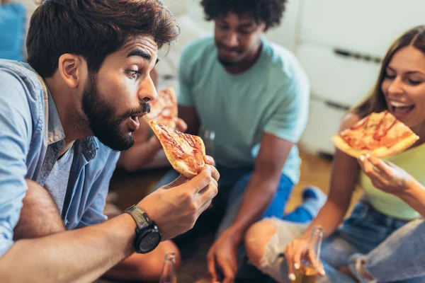 Группа этнических молодых друзей едят пиццу дома и хав — стоковое фото