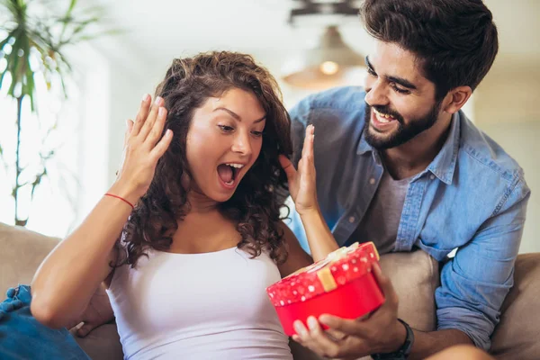 Hermosa pareja joven está celebrando en casa. Hombre guapo es g — Foto de Stock